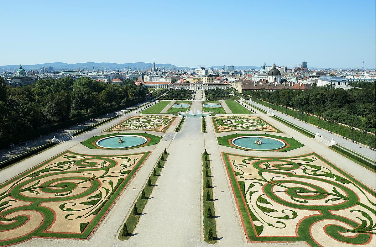 Der weitläufige Park vor dem Schloss mit kreisrunden Springbrunnen und kunstvoll angelegten Grünflächen. 