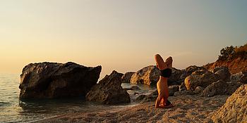 Eine Person macht Yoga am Strand. 