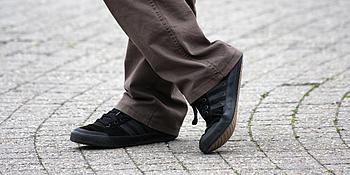 Beine eines Mannes in brauner Hose und schwarzen Schuhen im Freien 