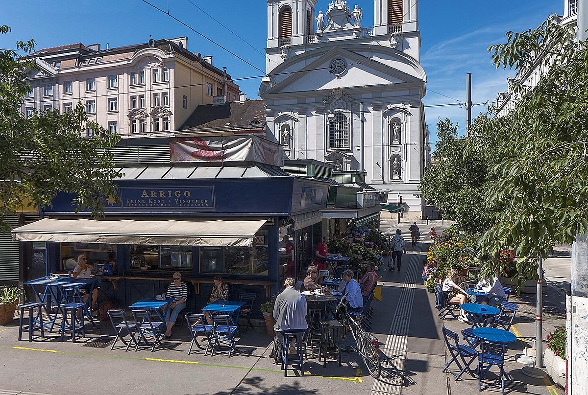 Menschen sitzen im Café Arrigo am Rochusmarkt in Wien