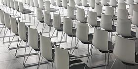 Hellgraue Stühle in Reihen in einem Seminarraum 