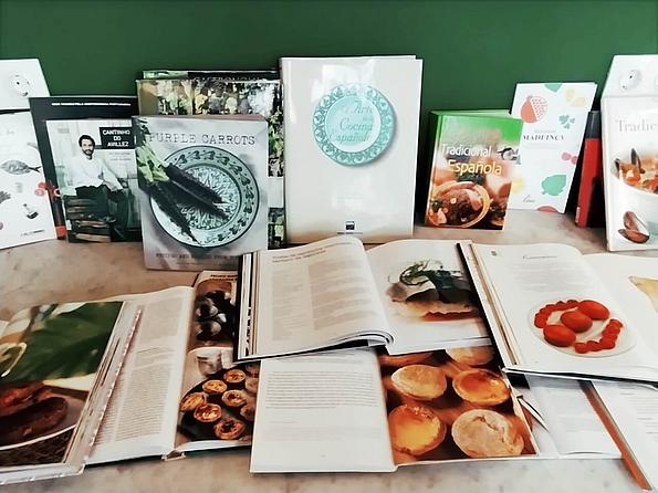 Eine Auswahl aufgeklappter mediterraner Kochbücher mit ansprechenden Bildern diverser Speisen