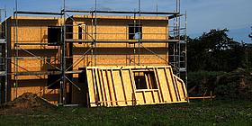 Niedrigenergiehaus im Rohbau mit Gerüst und Fertigteilwand aus Holz angelehnt