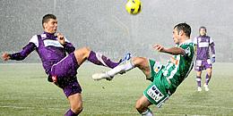 Ein Spieler in grün und einer in lila kämpfen um den Ball
