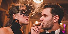 Frau mit Maske, ein Mann raucht Zigarre