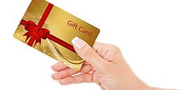 Eine Hand hält eine goldene Geschenkkarte mit roter Schleife