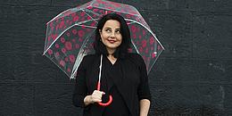 Nadja Maleh mit Regenschirm und verschmitztem Lächeln schaut nach oben