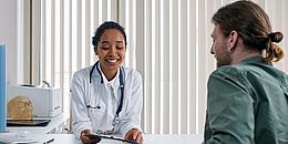 Das Bild zeigt eine Ärztin in einem Beratungsgespräch mit einem Patienten.