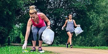 Mädchen beim Joggen sammeln gleichzeitig Müll ein