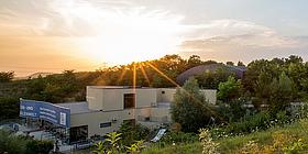Gebäude im Grünen dahinter Sonnenuntergang, die Fossilienwelt in Stetten
