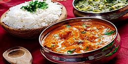 Indisches Curry in metallenem Topf, Reis als Beilad