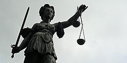 Statue von Justizia vor wolkengrauen Hintergrund