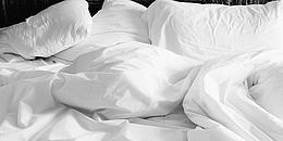 Weiße Bettwäsche die zum Schlafen einlädt