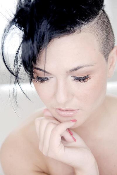 Frau mit Kurzharschnitt in der Farbe schwarz, seitlich sind die Haare abrasiert
