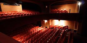 Ein Kinosaal mit rot-orangenen Sesseln im Parterre sowie in den Logen darüber