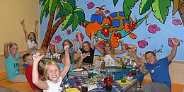Jubelnde Kinder um einen Tisch versammelt bei einem Geburtstagsfest im Haus des Meeres