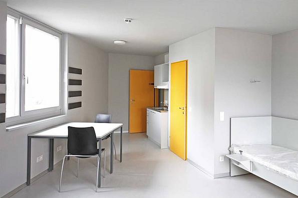 Einzelzimmer Studentenheim Base 11 mit schlichter Einrichtung und 2 gelben Türen.