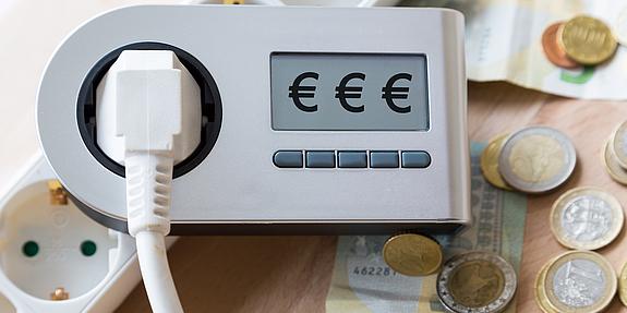 Stromrechner liegt auf Tisch mit Kleingeld im Hintergrund.