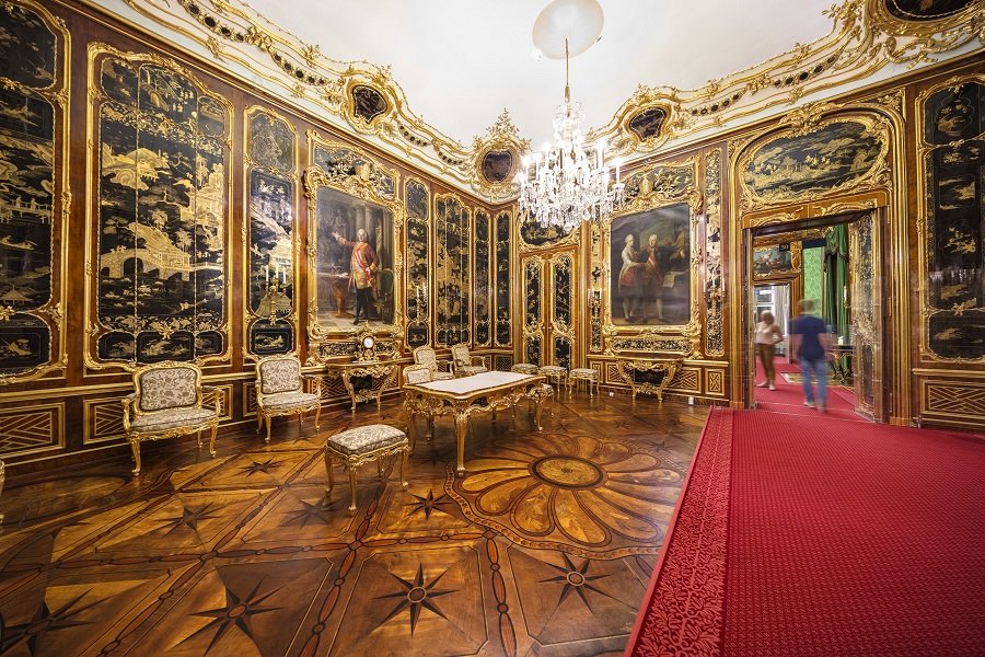 Prunkvoller Raum, roter Teppich, große Gemälde