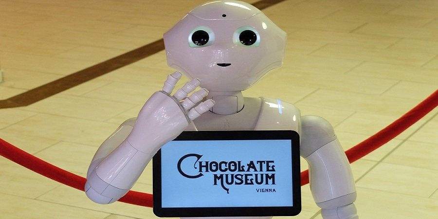 Roboter, der Tablett in der Hand hält, auf dem das Logo des Museums abgebildet ist