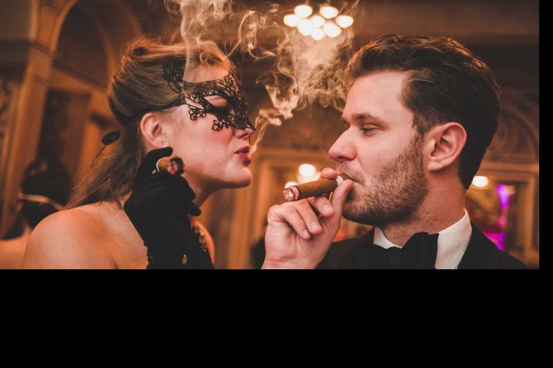 Frau mit Maske, ein Mann raucht Zigarre