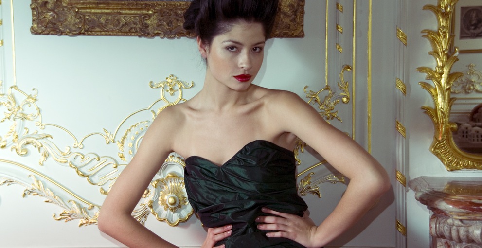 Model in schwarzem Kleid vor barocker Wand