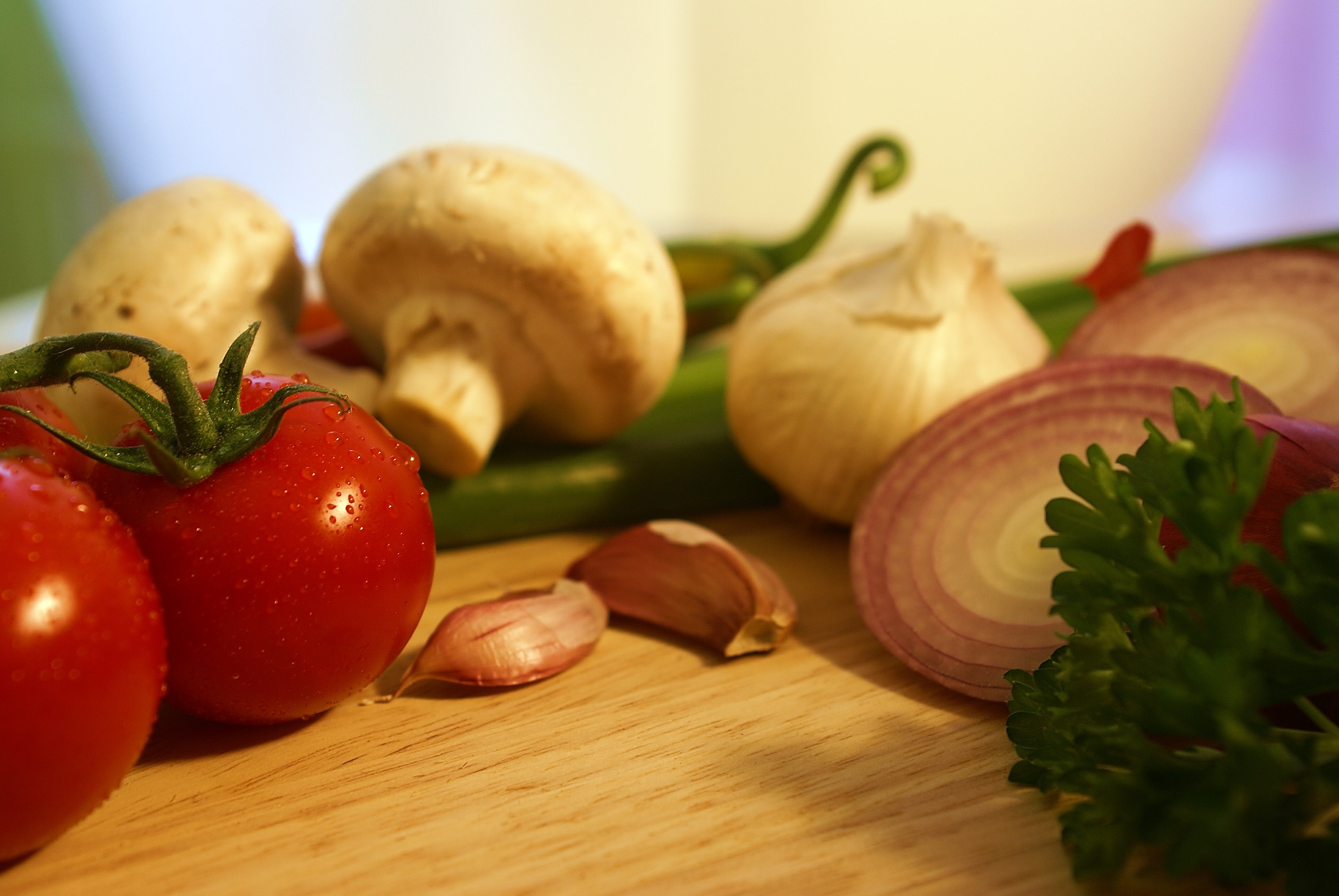 Gemüse (Tomaten, Champignons, Fisolen, Knoblauch, Zwiebeln, Petersilie) auf einer Anrichte 