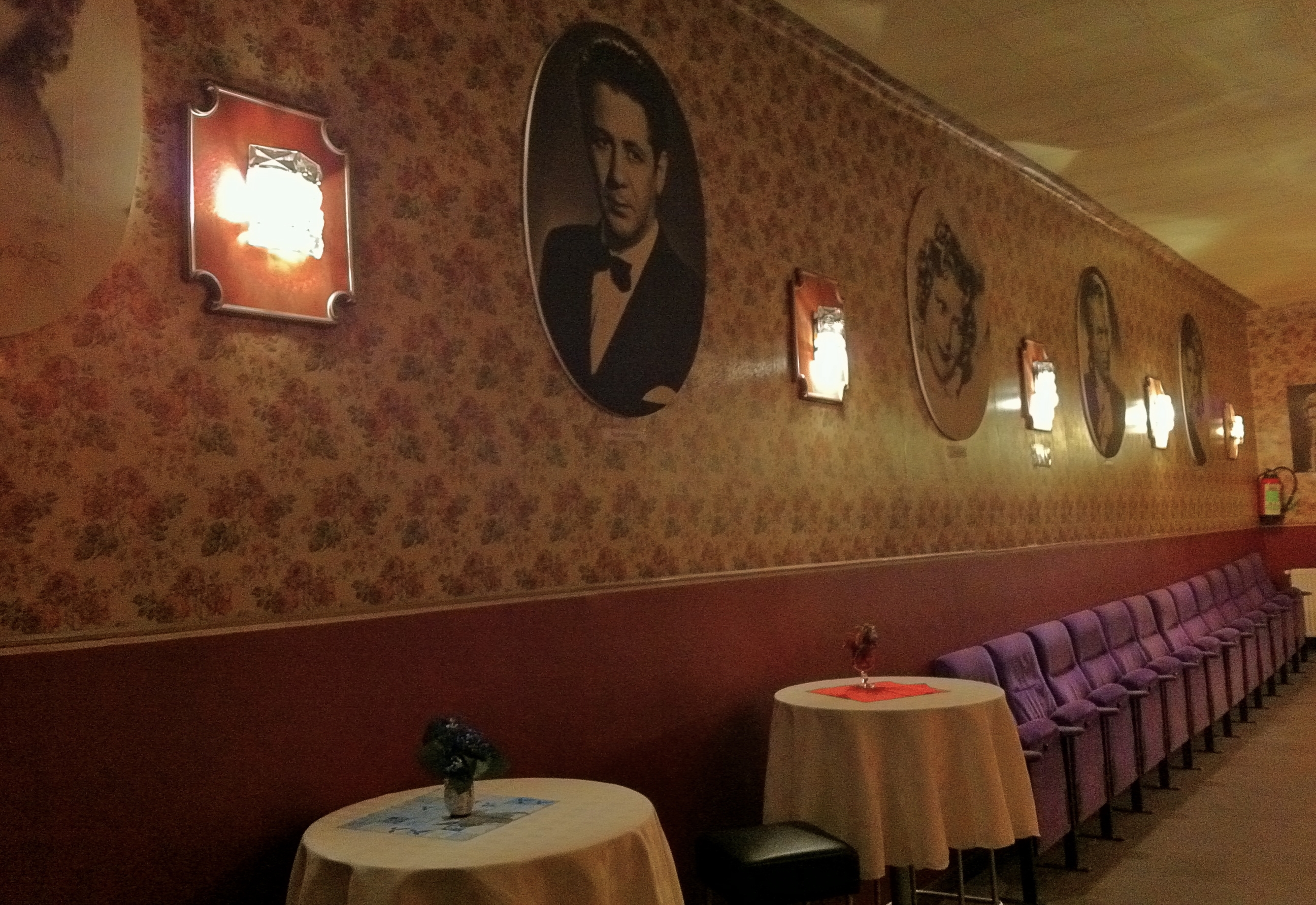 An der Wand hängen die Bilder vieler Filmlegenden, davor Kinosessel und kleine Tische mit Blumengestecken.