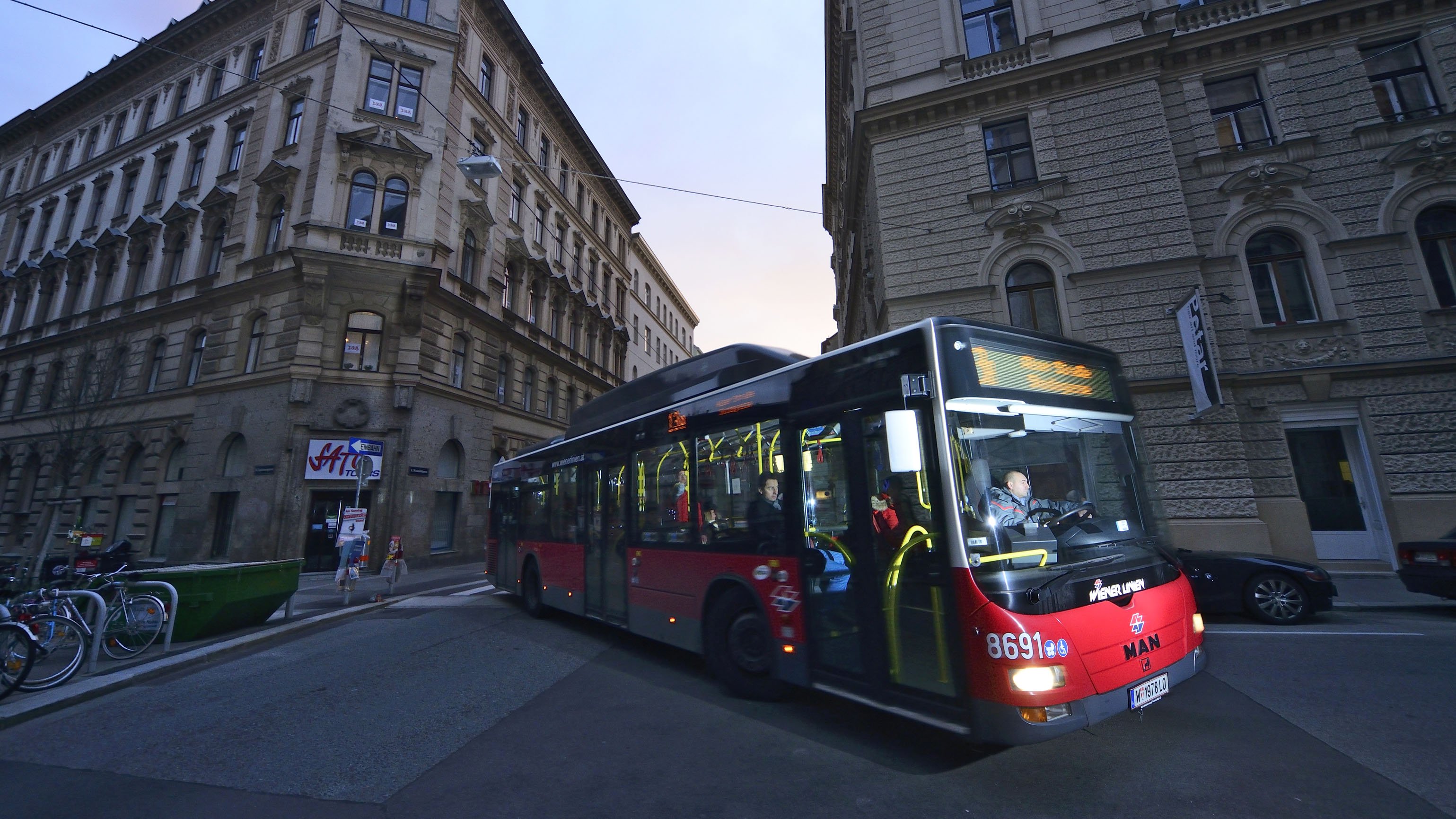 Bus der Wiener Linien schlängelt sich in der Dämmerung durch die Straßen.