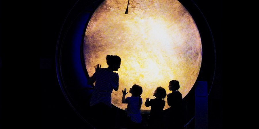 Kinder stehen mit Museumsangestellter vor Mond