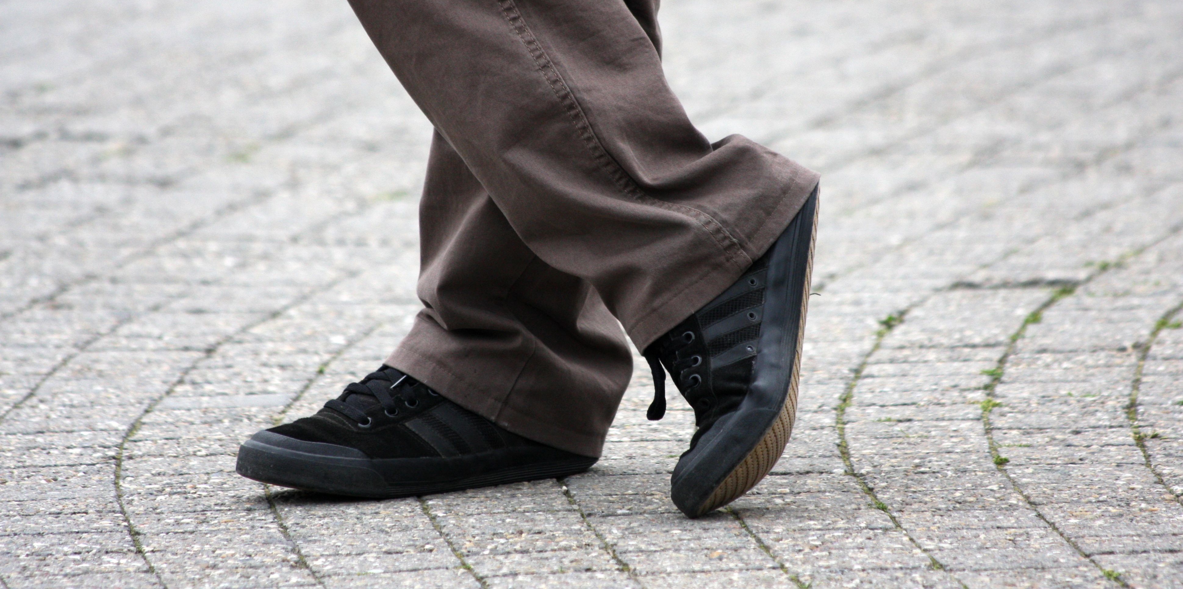 Beine eines Mannes in brauner Hose und schwarzen Schuhen im Freien 