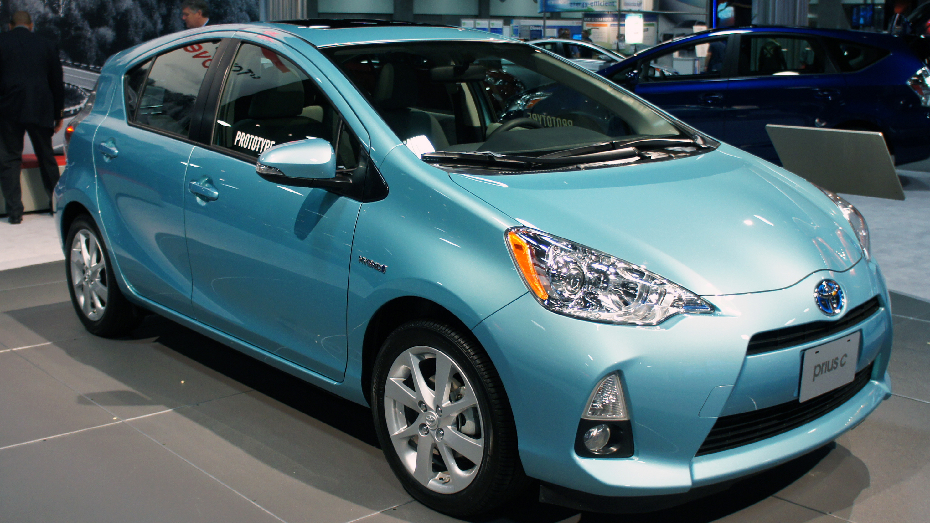 Bild von blauem Hybridauto, das auf einer Automesse präsentiert wird.