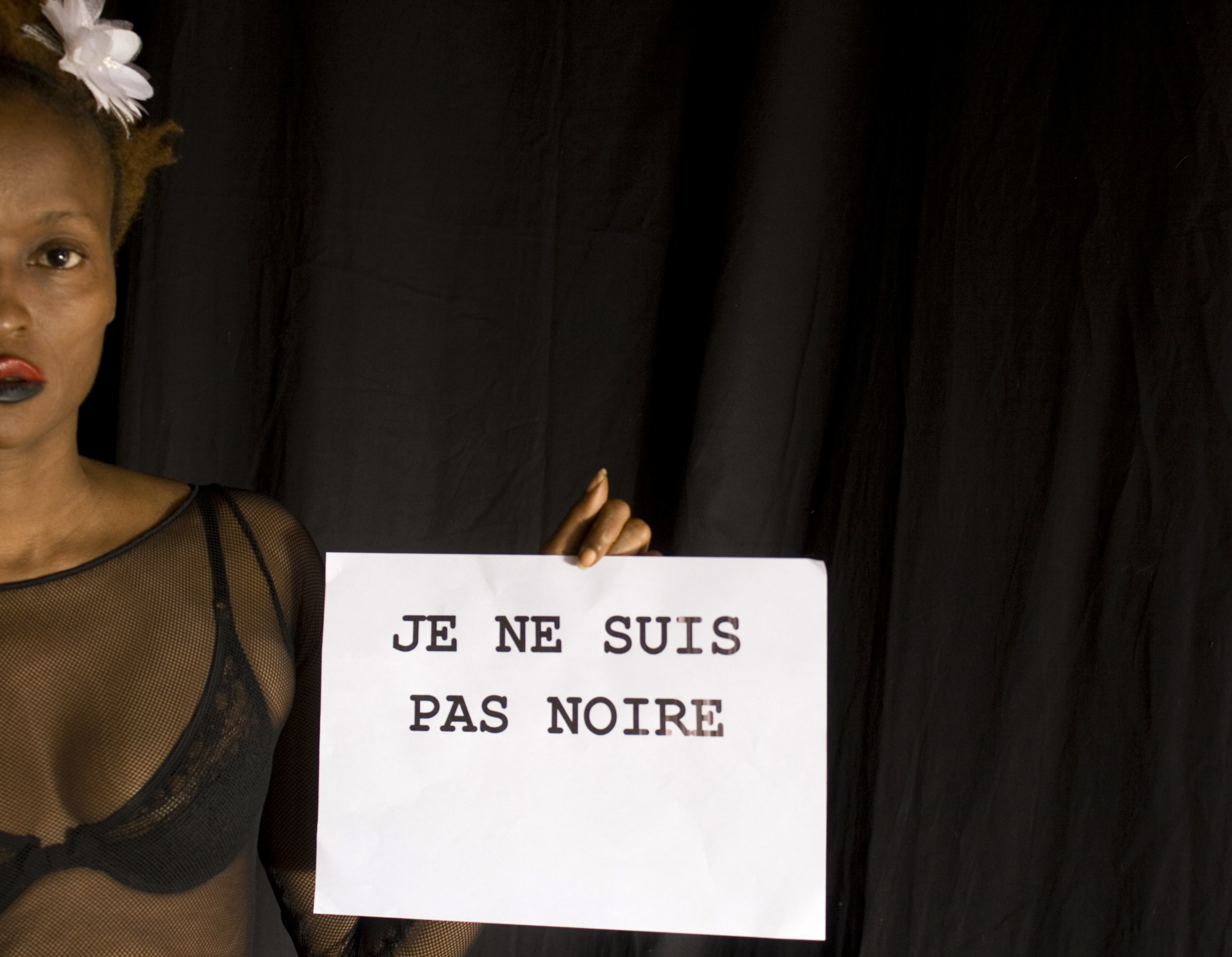 Frau mit dunkler Hautfarbe hält Schriftzug auf französisch "Je ne suis pas noire"