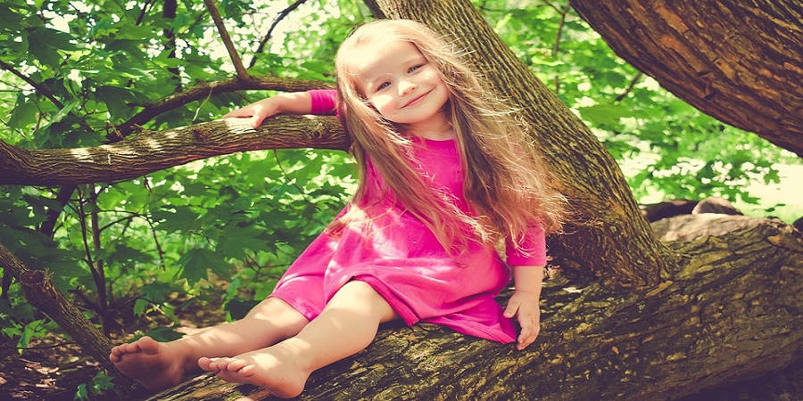 Kleines Mädchen in rosa Kleid auf Baum