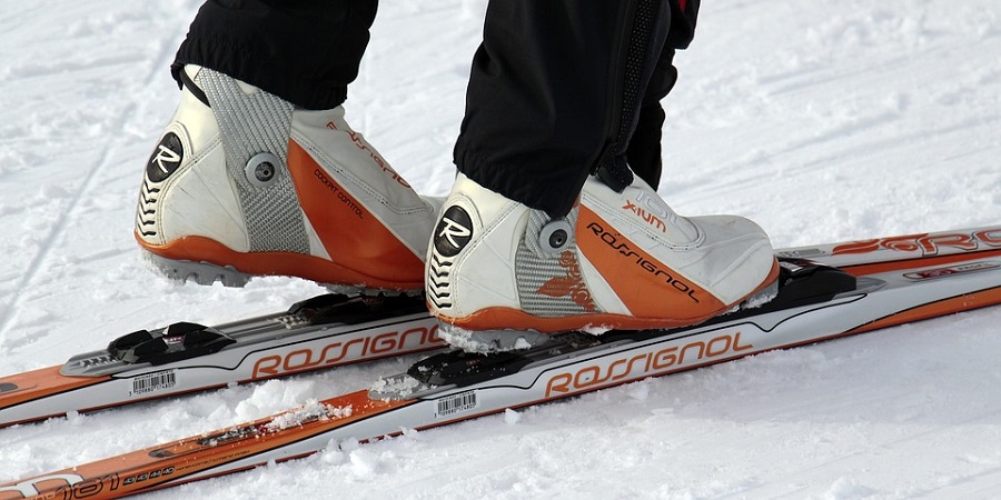 Close-Up von Langlaufschuhe und Langlaufskiern in weiß und orange.