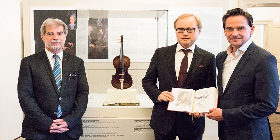 Drei Männer im Anzug vor Leopold Mozarts Violine