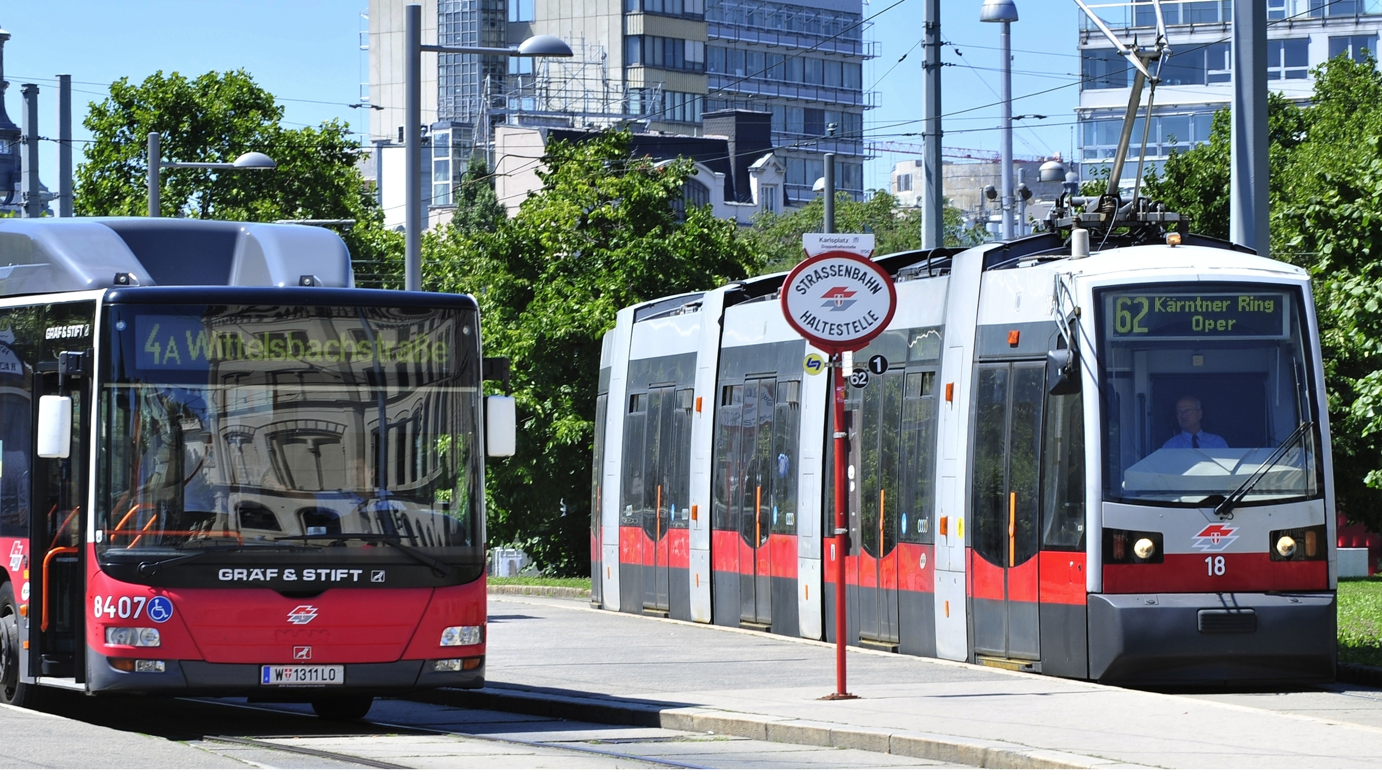 Autobus und Straßenbahn der Wiener Linien halten in einer Station.