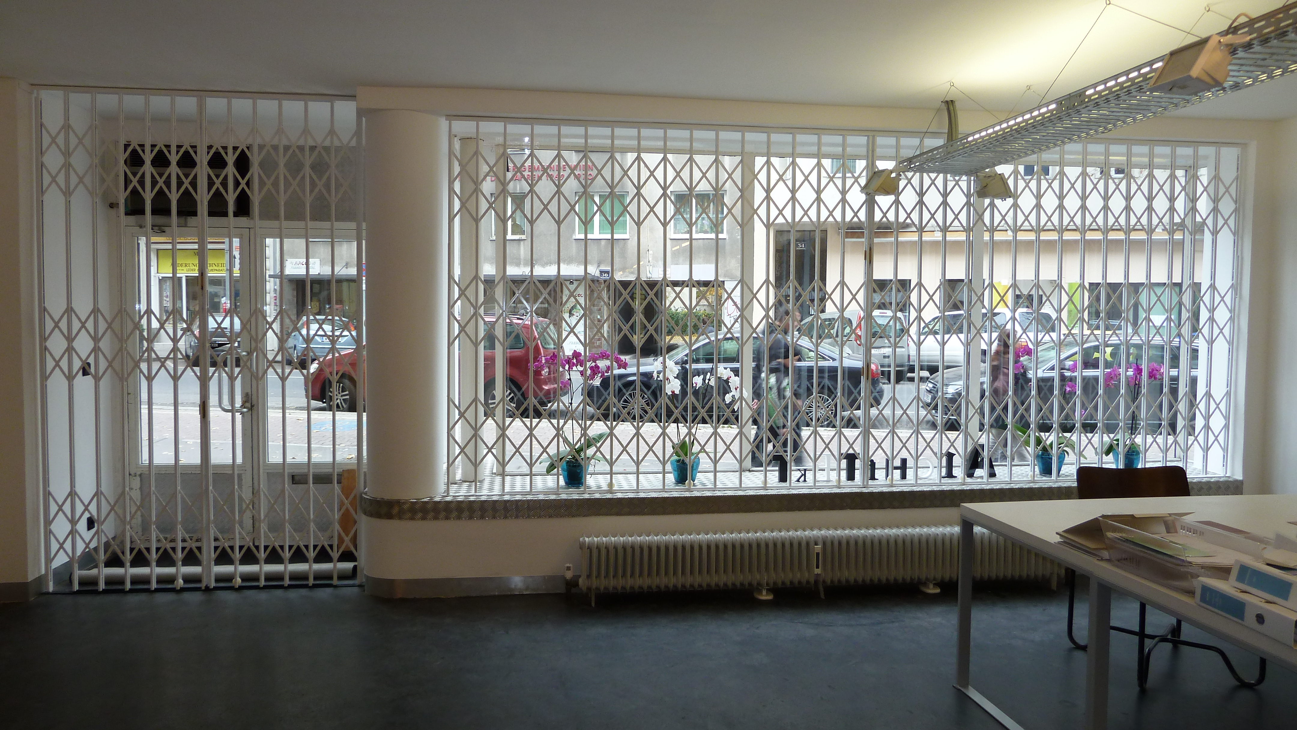 Weißes Scherengitter vor Tür und Fenster Innen eines Geschäftslokals