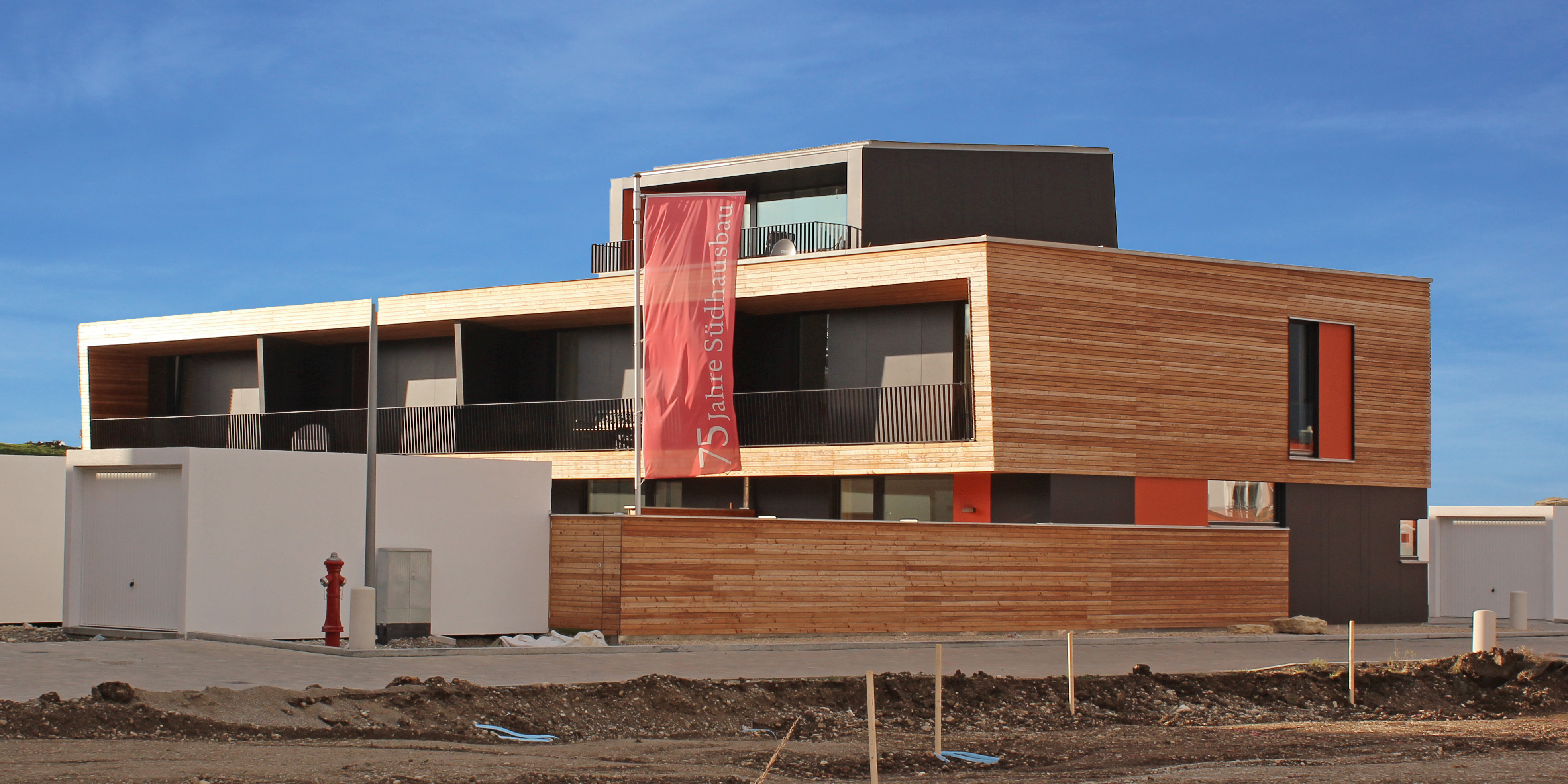 Passivhaus in modernen Architektenstil mit Holz und Glas vor blauem Himmel