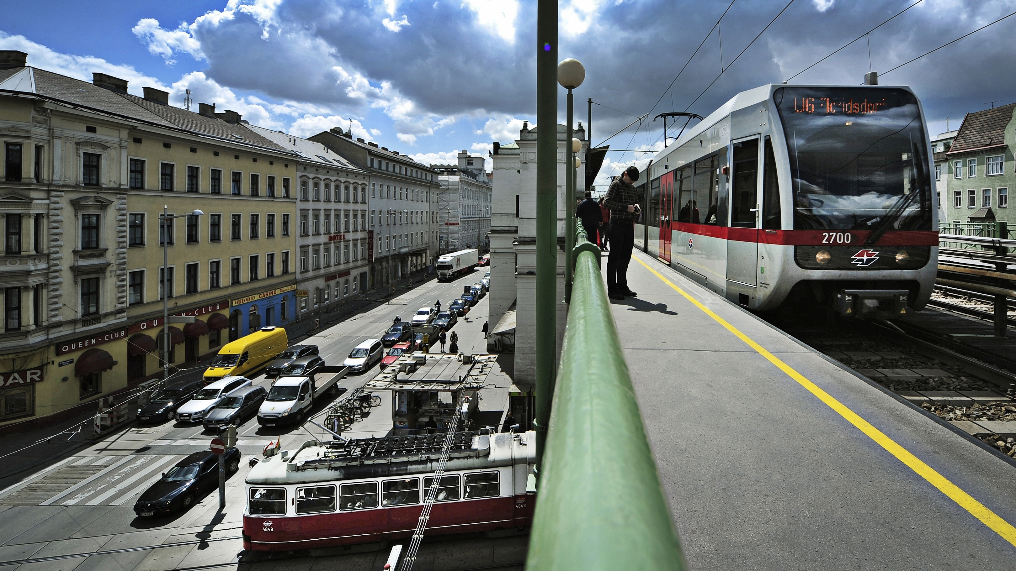 Bild von U-Bahn-Linie U6, die über die Brücke bei der Station Alser Straße fährt, während unter der Brücke eine Straßenbahn gerade ihre Station verlässt.