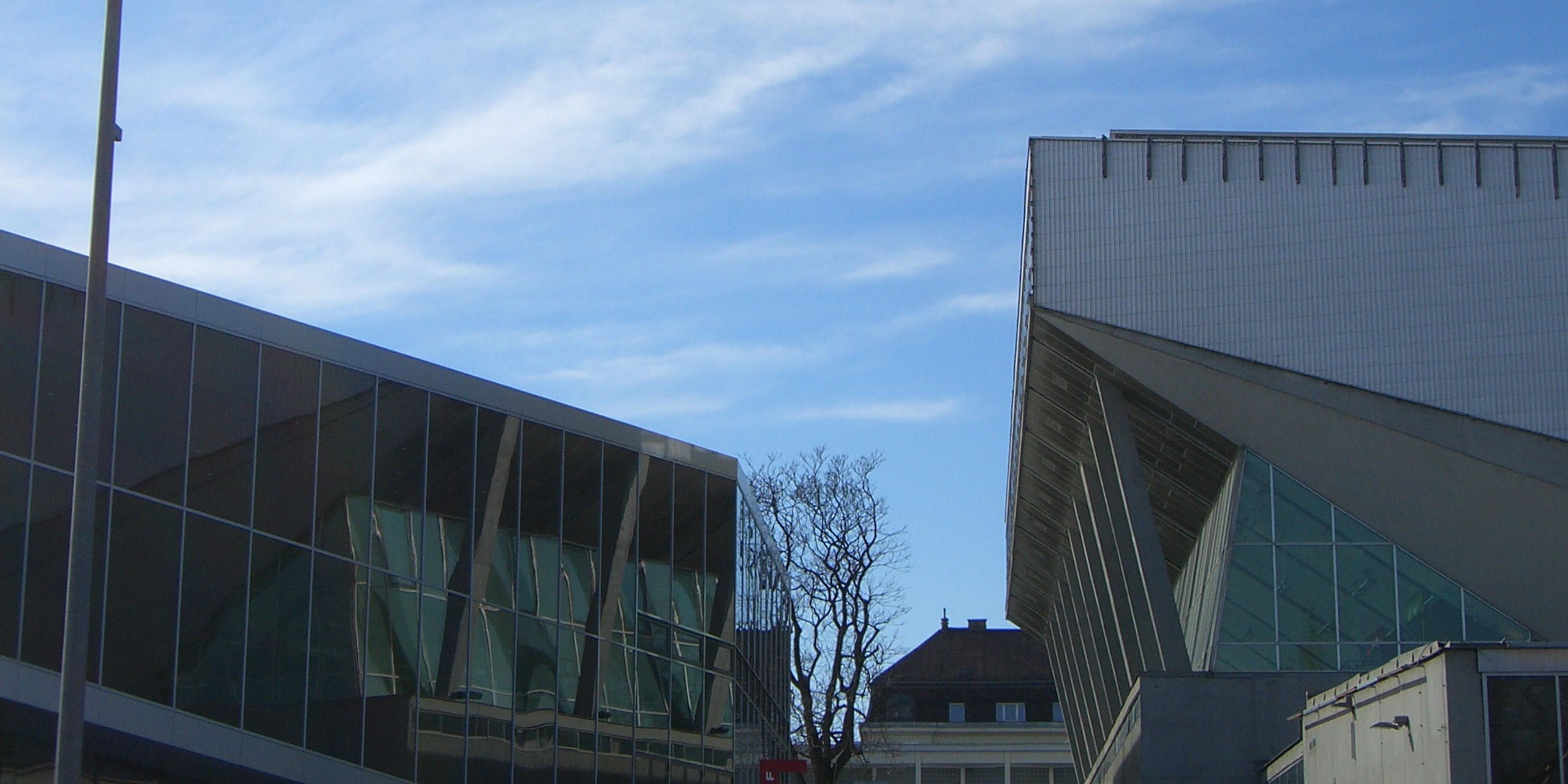 Architektonisch auffälliges, modernes Gebäude mit blauem Himmel im Hintergrund.