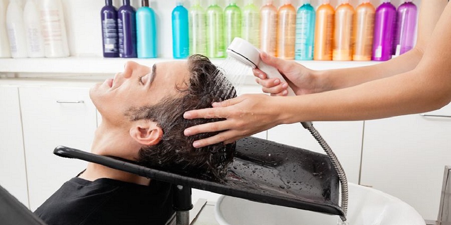 Mann lässt sich beim Friseur die Haare waschen