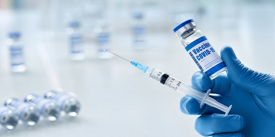 Hand mit blauem Handschuh hält Corona-Impfstoff und Spritze