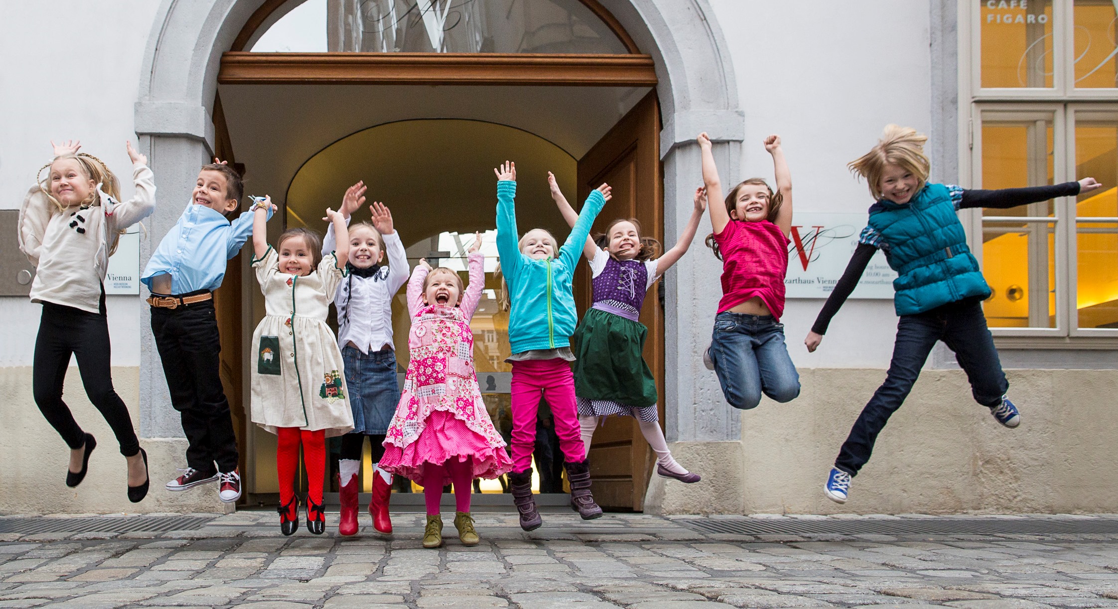Kinder machen Luftsprünge vor dem Mozarthaus Vienna
