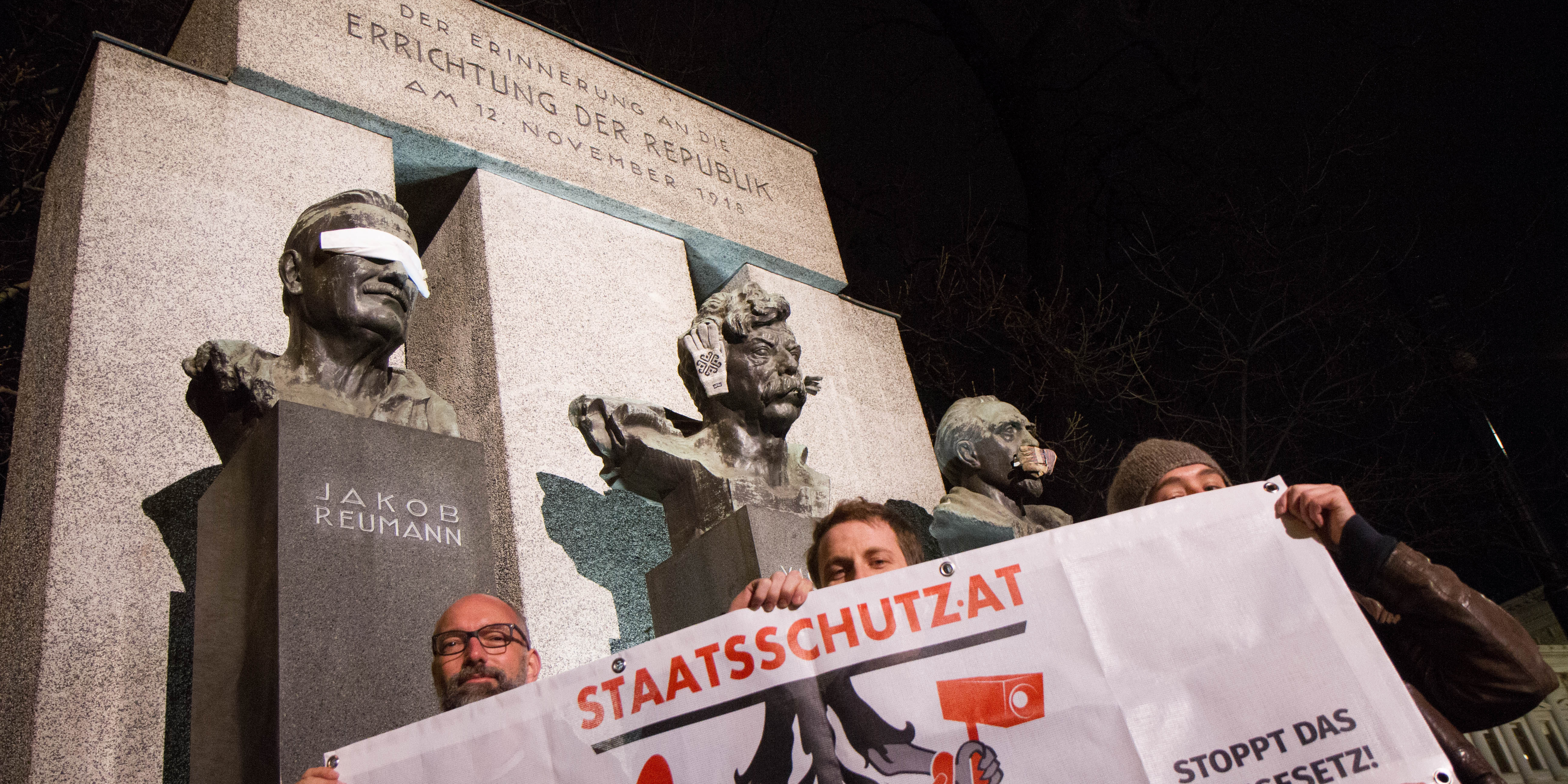 Drei Personen halten Banner "Stoppt das Staatsschutzgesetz" vor dem Denkmal der Errichtung der Republik.
