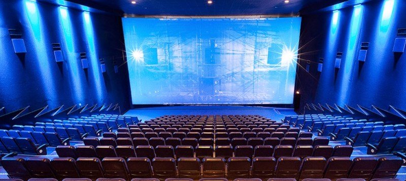 Eines der größten Kinosääle im Apollo Wien, mit blauer Beleuchtung und großer Leinwand