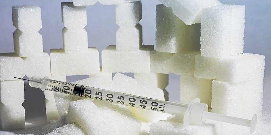Zuckerpyramide im Vordergrund eine Spritze mit Insulin