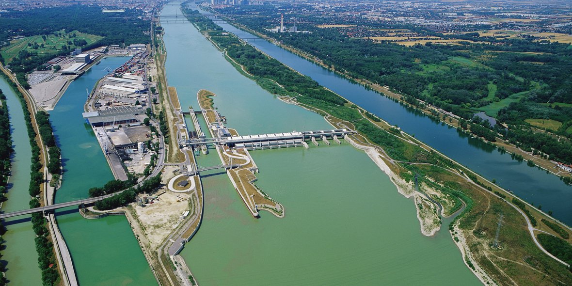 Links im Bild das schmale Band des Donaukanals, in der Mitte das Becken des Winterhafens, von der Donau durch die rechte Baugrube getrennt. Rechts der Donau beim Blick stromaufwärts die Donauinsel und im rechten oberen Eck noch ein Teil der Neuen Donau.