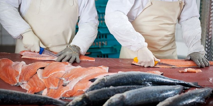 Zwei Menschen die Lachs schneiden auf einem Fischmarkt