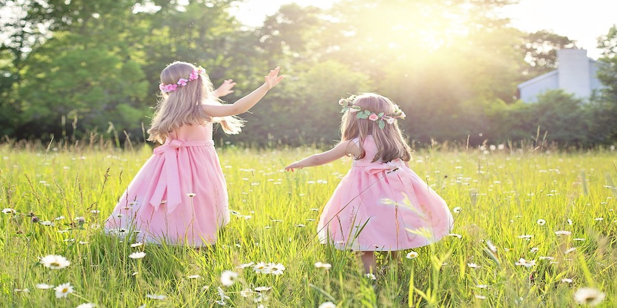 Zwei Mädchen mit rosa Kleid in einer Blumenwiese